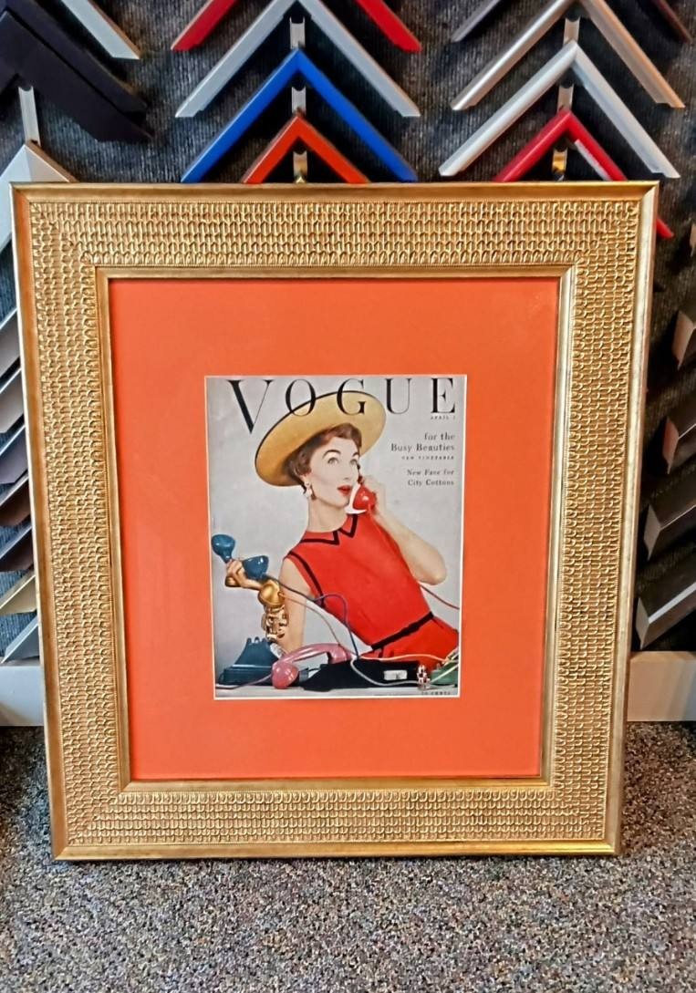 A Vogue magazine cover framed with an orange mat and gold frame